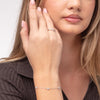 Close-up of a woman's hand wearing a ring and bracelet on a neutral background