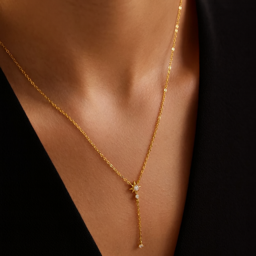 Gold necklace with a star-shaped pendant on a person's neck against a black background