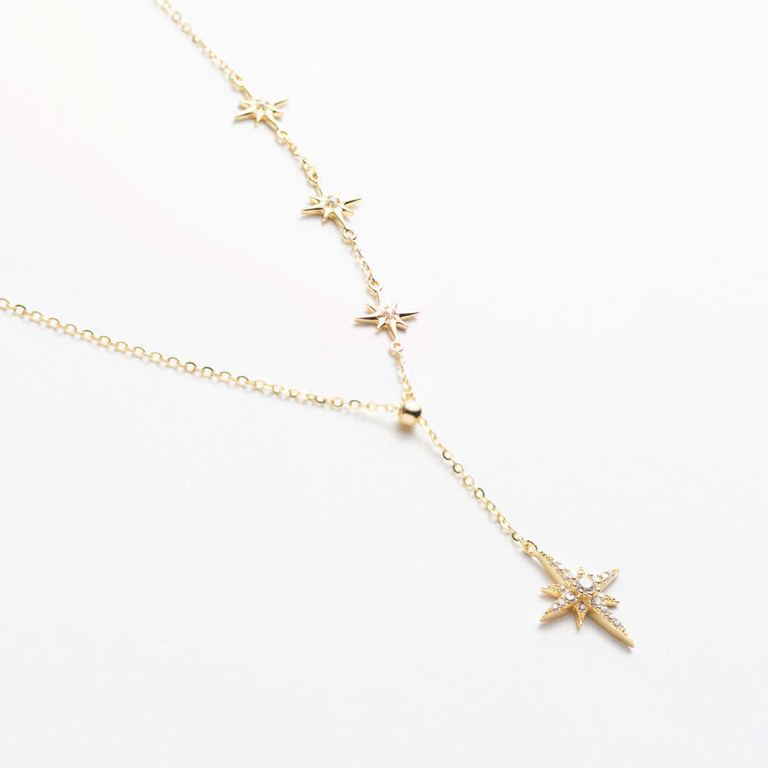 Gold necklace with star-shaped pendants on a white background