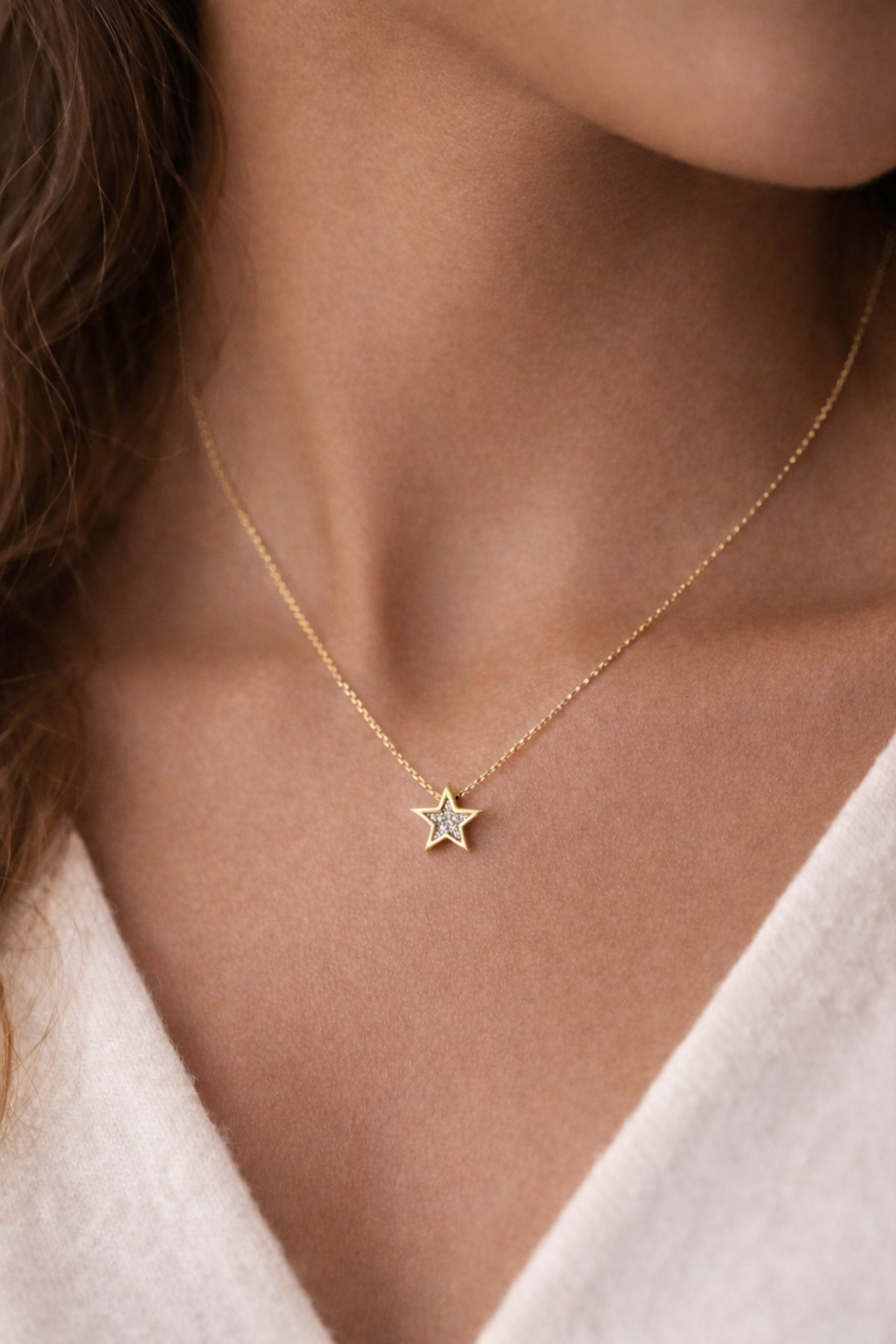 Gold necklace with a star pendant worn by a person