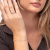 Woman wearing a silver bracelet and ring on a neutral background